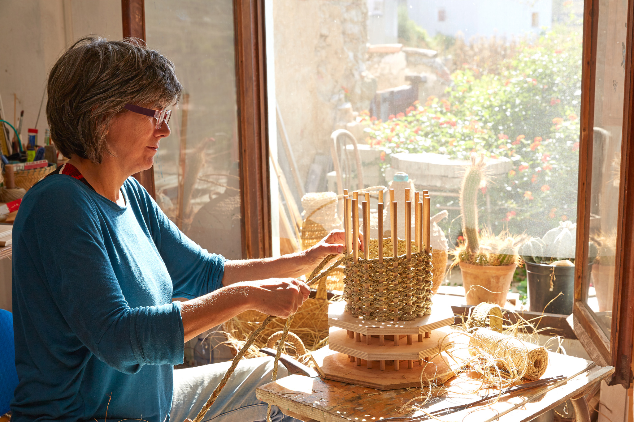 Foto de una mujer trabajando en un taller haciendo cestas de mimbre