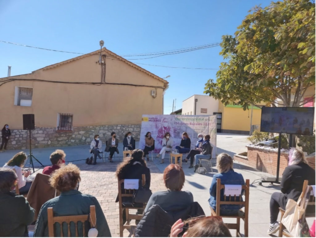 Foto de una charla de varias mujeres, con público, situada en la plaza de un pueblo